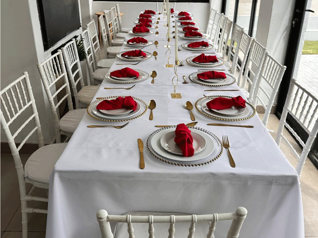 Formal event table setting with white chairs and red place settings